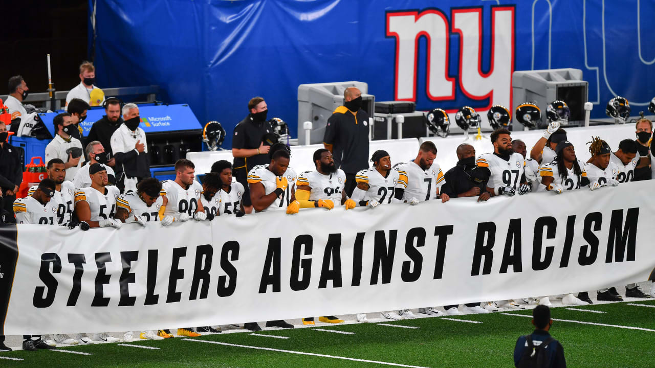 Pittsburgh Steelers fans stand with a banner reading WE WILL