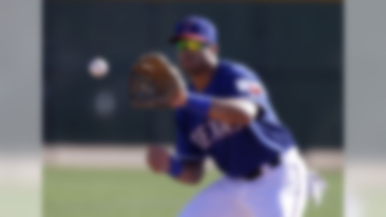 Seattle Seahawks quarterback Russell Wilson reaches up to grab a throw as he works out with the Texas Rangers during spring training baseball practice, Monday, March 3, 2014, in Surprise, Ariz. (AP Photo/Tony Gutierrez)