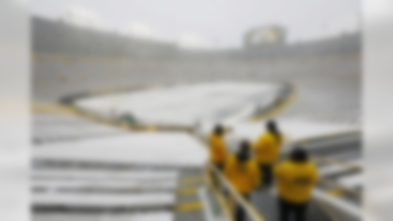 Event staff look out at a snow covered Lambeau Field before an NFL football game between the Green Bay Packers and the Arizona Cardinals on Sunday, Dec. 2, 2018, in Green Bay, Wis. (AP Photo/Mike Roemer)