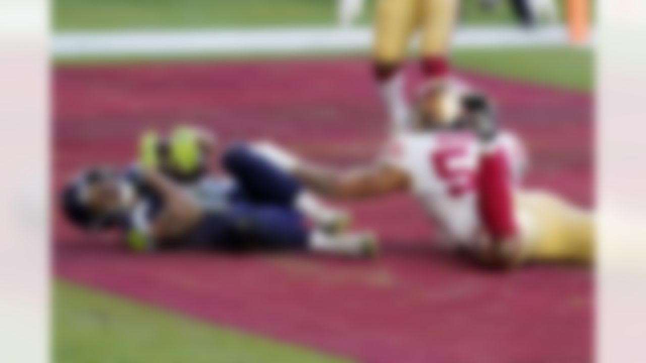 Seattle Seahawks wide receiver Tyler Lockett scores a touchdown as San Francisco 49ers middle linebacker Fred Warner (54) defends during the second half of an NFL football game, Sunday, Jan. 3, 2021, in Glendale, Ariz.
