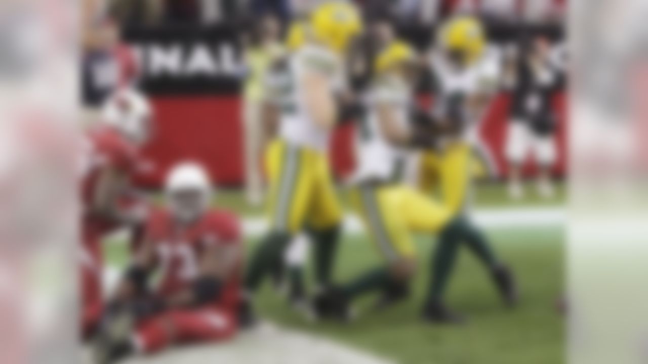 Green Bay Packers' Charles Woodson, second from right, celebrates his interception return for a touchdown with teammates Jarrett Bush (24) and Clay Matthews, front left, and Atari Bigby, back, as Arizona Cardinals' Jeremy Bridges (73) sits on the ground near teammate Beanie Wells, left, in the second quarter of an NFL football game Sunday, Jan. 3, 2010, in Glendale, Ariz. The Packers defeated the Cardinals 33-7. (AP Photo/Ross D. Franklin)