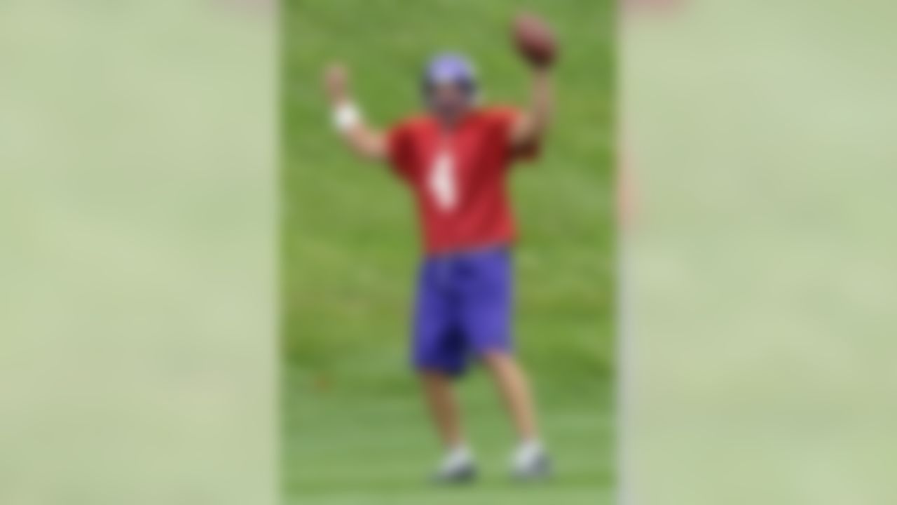 A ballboy lobs a ball as Minnesota Vikings quarterbacks Tarvaris Jackson,  left, rookie Joe Webb, center and Sage Rosenfels, right, head to another  practice field at the NFL team's football training camp