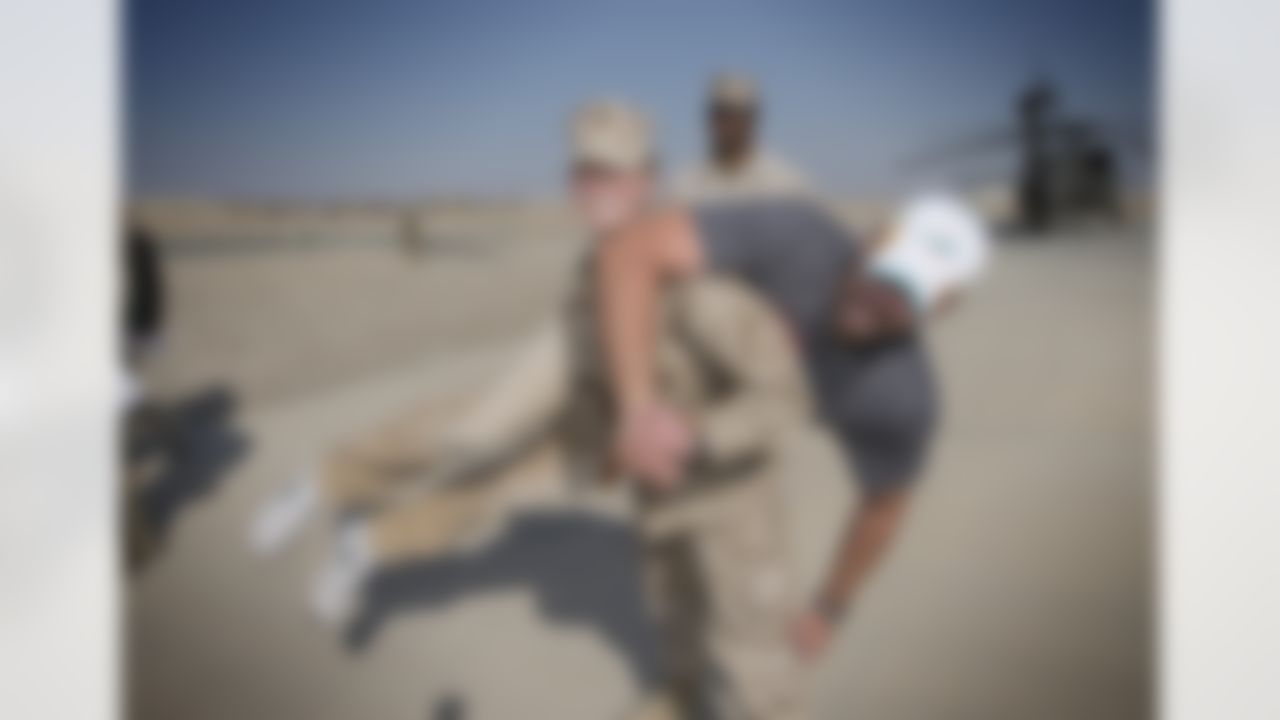 Lt. Skye Martin of the US Marine Corps performs a fireman's "Carry of the Day" with Miami Dolphins' Brandon Fields, who towered above her shorter frame - while at the "Dust Off" airfield for a military hospital in the Middle East on March 5, 2014. Fields is in the region with Pierre Garcon of the Washington Redskins and Jimmy Graham of the New Orleans Saints as part of a six-day USO/NFL tour designed to make �Every Moment Count� with troops. This is the trio's first-ever USO experience. (USO Photo by Dave Gatley)