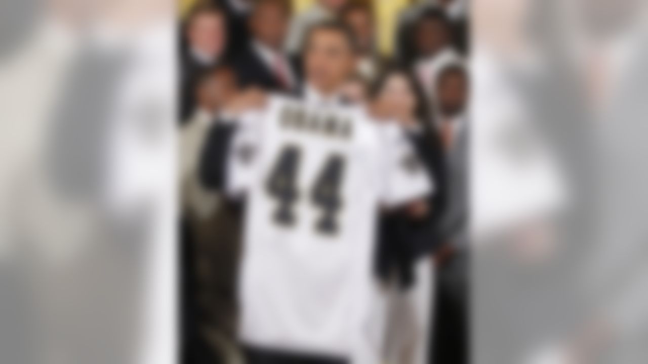 President Barack Obama holds up a personalized New Orleans Saints football team jersey as he stands with the 2009 NFL Super Bowl Football Champions New Orleans Saints, Monday, Aug. 9, 2010, during a ceremony in the East Room of the White House in Washington honoring the team. (AP Photo/Charles Dharapak)