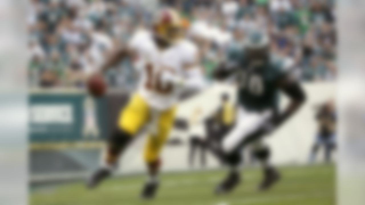 Washington Redskins quarterback Robert Griffin III, left, scrambles past Philadelphia Eagles nose tackle Bennie Logan during the first half of an NFL football game in Philadelphia, Sunday, Nov. 17, 2013. (AP Photo/Matt Slocum)