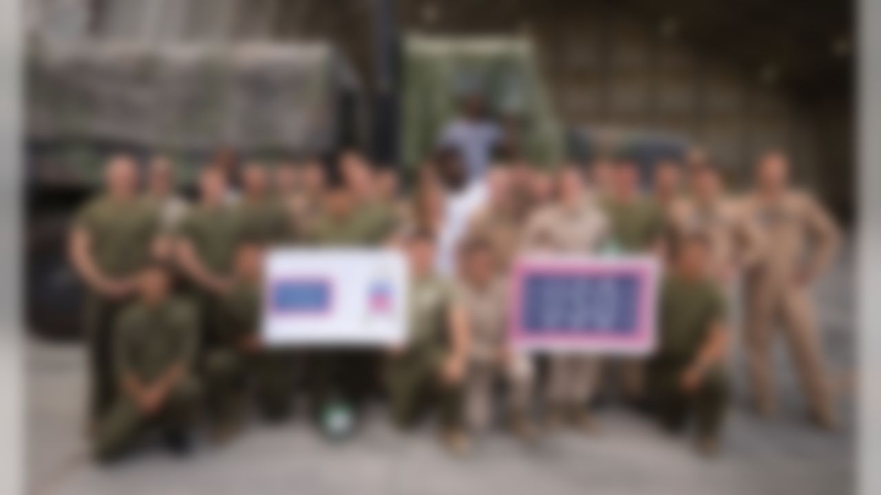 New Orleans Saints defensive end Cameron Jordan (back row 3rd l),   Tennessee Titans tight end Delanie Walker (back row c), and Miami Dolphins cornerback Byron Maxwell (back row c standing on truck) pose for a photo with service members during a USO tour visit in the U.S. Fifth Fleet Area of Operations, April 8, 2017. The USO and NFL are celebrating a 51-Year Partnership with Weeklong Tour to Southwest Asia, Complete with Unit Visits, Military-Themed Athletic Competitions and Distribution of USO2GO Kits. (Fred Greaves/USO)