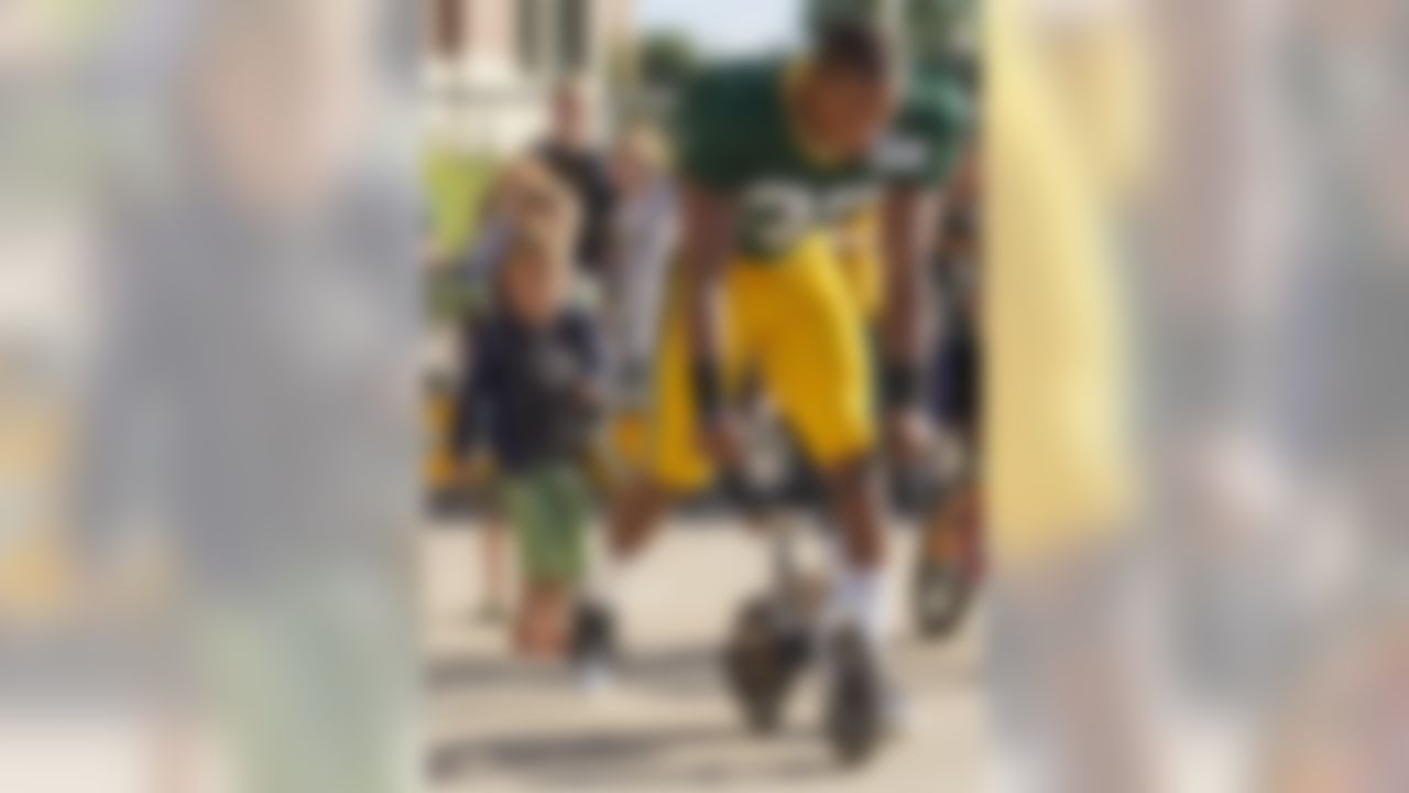 Green Bay Packers defensive back Micah Pellerin (32) eyes up if a young childs bike is big enough to ride before NFL football training camp Saturday, July. 28, 2012, in Green Bay, Wis. (AP Photo/Mike Roemer)