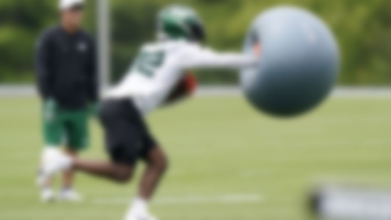 New York Jets running back La'Mical Perine fends off an airborne exercise ball thrown at him as he carries the ball during NFL football practice, Wednesday, June 2, 2021, in Florham Park, N.J.