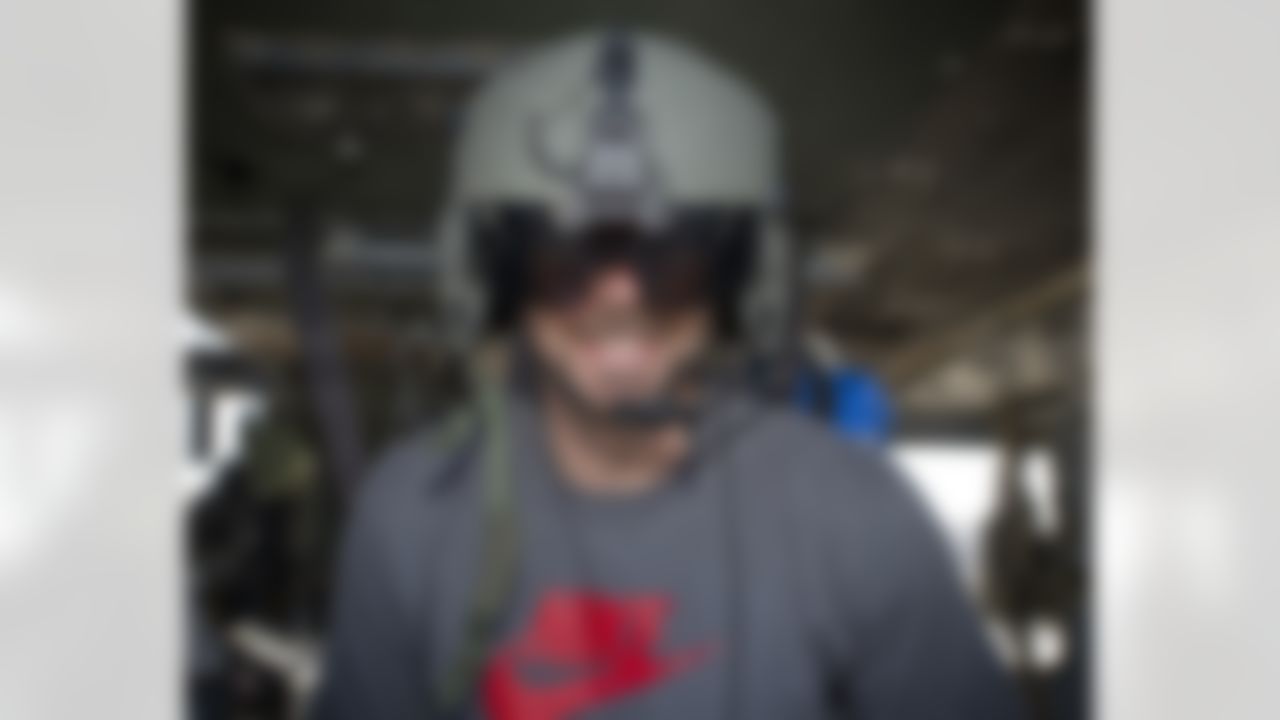 Brandon Fields of the Miami Dolphins tries on a helmet and sits inside a Blackhawk helicopter during one of many USO/NFL stops in the Middle East on March 5, 2014. This is Fields first USO experience. (USO Photo by Dave Gatley)