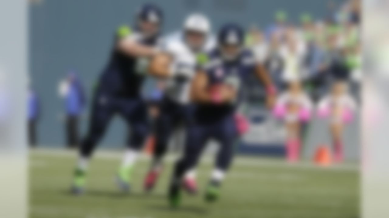 Seattle Seahawks quarterback Russell Wilson, right, runs the ball as Tennessee Titans' Karl Klug, center, and Seahawks' Paul McQuistan, left, pursue during the first half of an NFL football game, Sunday, Oct. 13, 2013, in Seattle. (AP Photo/Elaine Thompson)