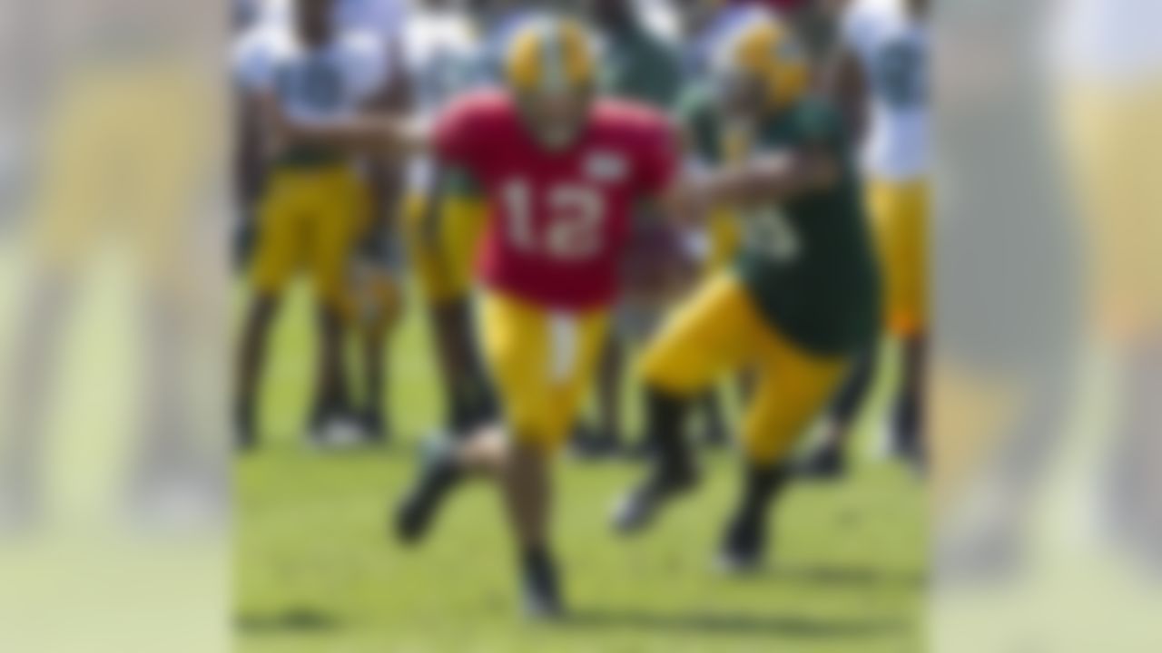 Green Bay Packers quarterback Aaron Rodgers (12) tries to get away from the defensive pressure of defensive end Jerel Worthy (99) during NFL football training camp Saturday, July. 28, 2012, in Green Bay, Wis. (AP Photo/Mike Roemer)