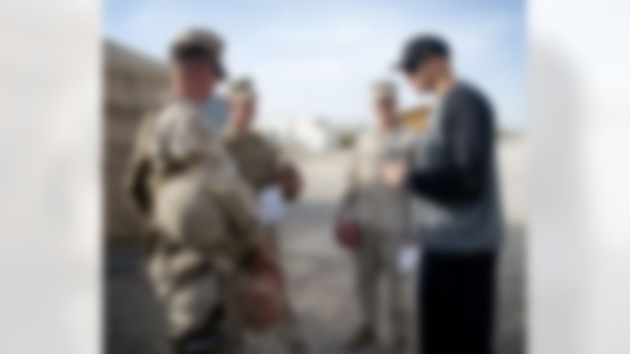 Continuing a time honored USO/NFL tradition, Brandon Fields of the Miami Dolphins, Pierre Garcon of the Washington Redskins and Jimmy Graham of the New Orleans Saints pose for a group of troops stationed in the Middle East on March 4, 2014. This is the trio's first USO/NFL tour. (USO Photo by Dave Gatley)