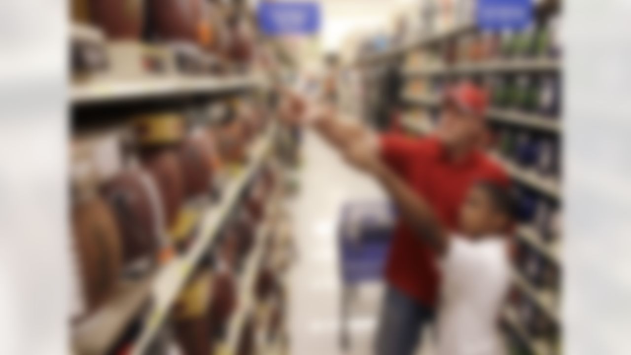 Houston Texans rookie defensive end J.J. Watt, left, helps Damon Holland, 12, pick out a football, Tuesday, Dec. 13, 2011, in Houston. Houston Texans rookies helped 30 children from the YMCA and Boys and Girls club shop with their gift cards from Academy. (AP Photo/David J. Phillip)