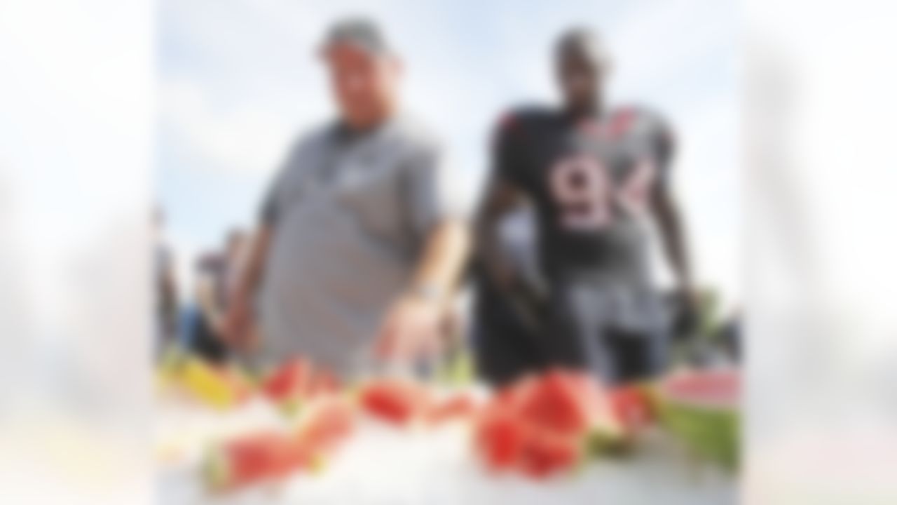 New Orleans Saints defensive line coach Bill Johnson joins Houston Texans defensive end Antonio Smith (94) for watermelon after practice at NFL football training camp in Metairie, La., Thursday, Aug. 19, 2010. The Saints and the Texans are holding joint practice session leading up to their preseason game on Saturday night.  (AP Photo/Bill Haber)