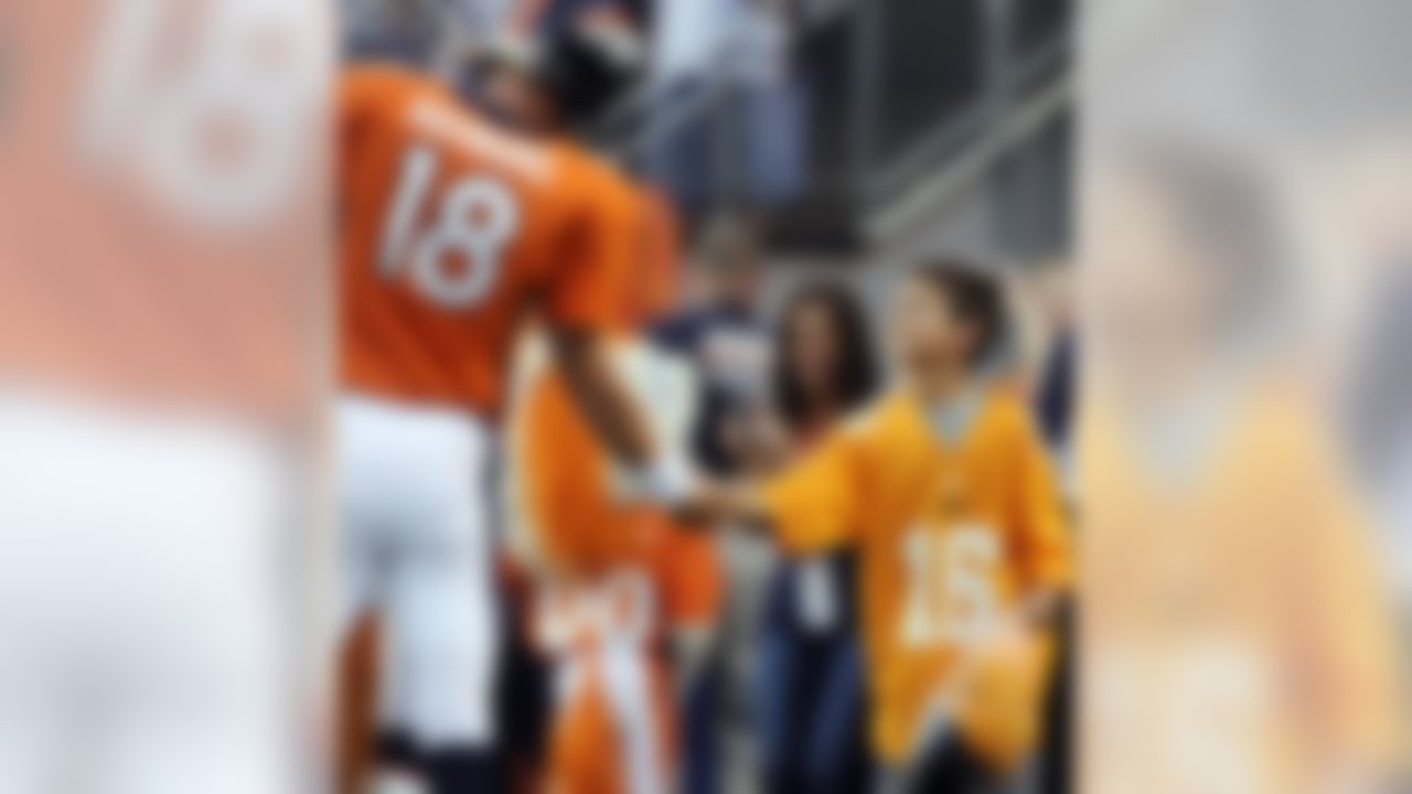 A youngster reaches to shake the hand of Denver Broncos quarterback Peyton Manning (18) before a preseason NFL football game against the Arizona Cardinals, Thursday, Aug. 29, 2013, in Denver. (AP Photo/Jack Dempsey)