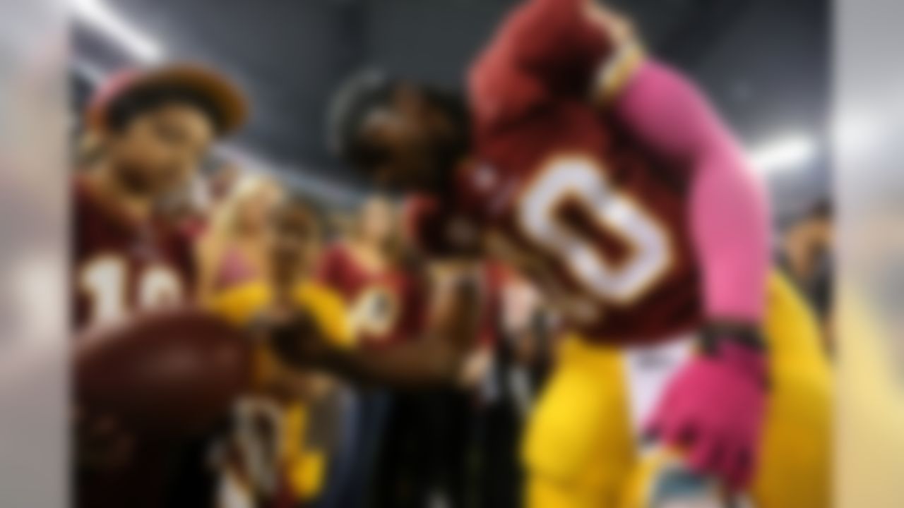 Washington Redskins quarterback Robert Griffin III signs an autograph for a fan after warming up before an NFL football game against the Dallas Cowboys, Sunday, Oct. 13, 2013, in Arlington, Texas. (AP Photo/LM Otero)