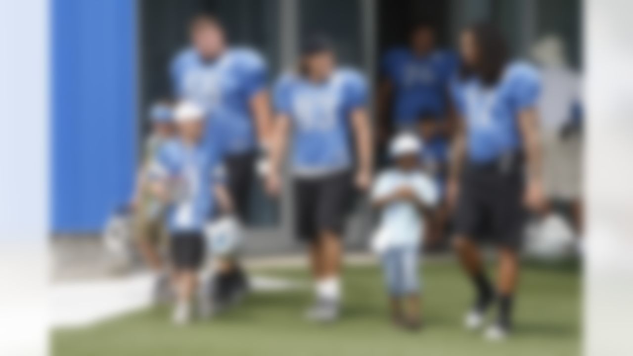 Detroit Lions guard Stephen Peterman (66) receiver Tim Toone (83) guard Roy Schuening and receiver Mike Moore (17) walk out with season ticket holder's children before the start of their training camp in Allen Park, Mich., Sunday, Aug. 1, 2010. (AP Photo/Carlos Osorio)