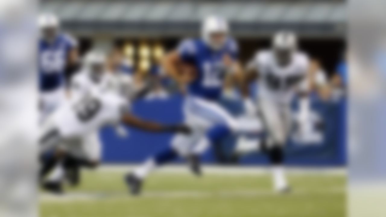 Indianapolis Colts quarterback Andrew Luck, center, cuts between Oakland Raiders cornerback Brandian Ross, left, and defensive end Lamarr Houston after being chased from the pocket during the second half of an NFL football game in Indianapolis, Sunday, Sept. 8, 2013. (AP Photo/AJ Mast)