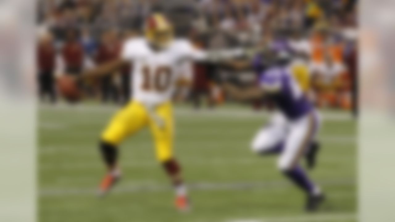 Washington Redskins quarterback Robert Griffin III, left, tries to break away from Minnesota Vikings outside linebacker Marvin Mitchell during the first half of an NFL football game Thursday, Nov. 7, 2013, in Minneapolis. (AP Photo/Ann Heisenfelt)