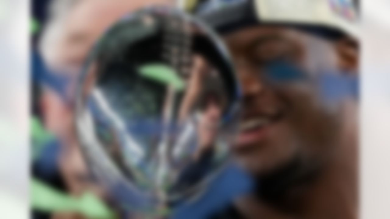 Seattle Seahawks running back Kenneth Walker III (9) holds the Lombardi Trophy with head coach Mike Macdonald and quarterback Sam Darnold (14) are seen in the reflection after a win over the New England Patriots in the NFL Super Bowl LX football game Sunday, Feb. 8, 2026, in Santa Clara, Calif.